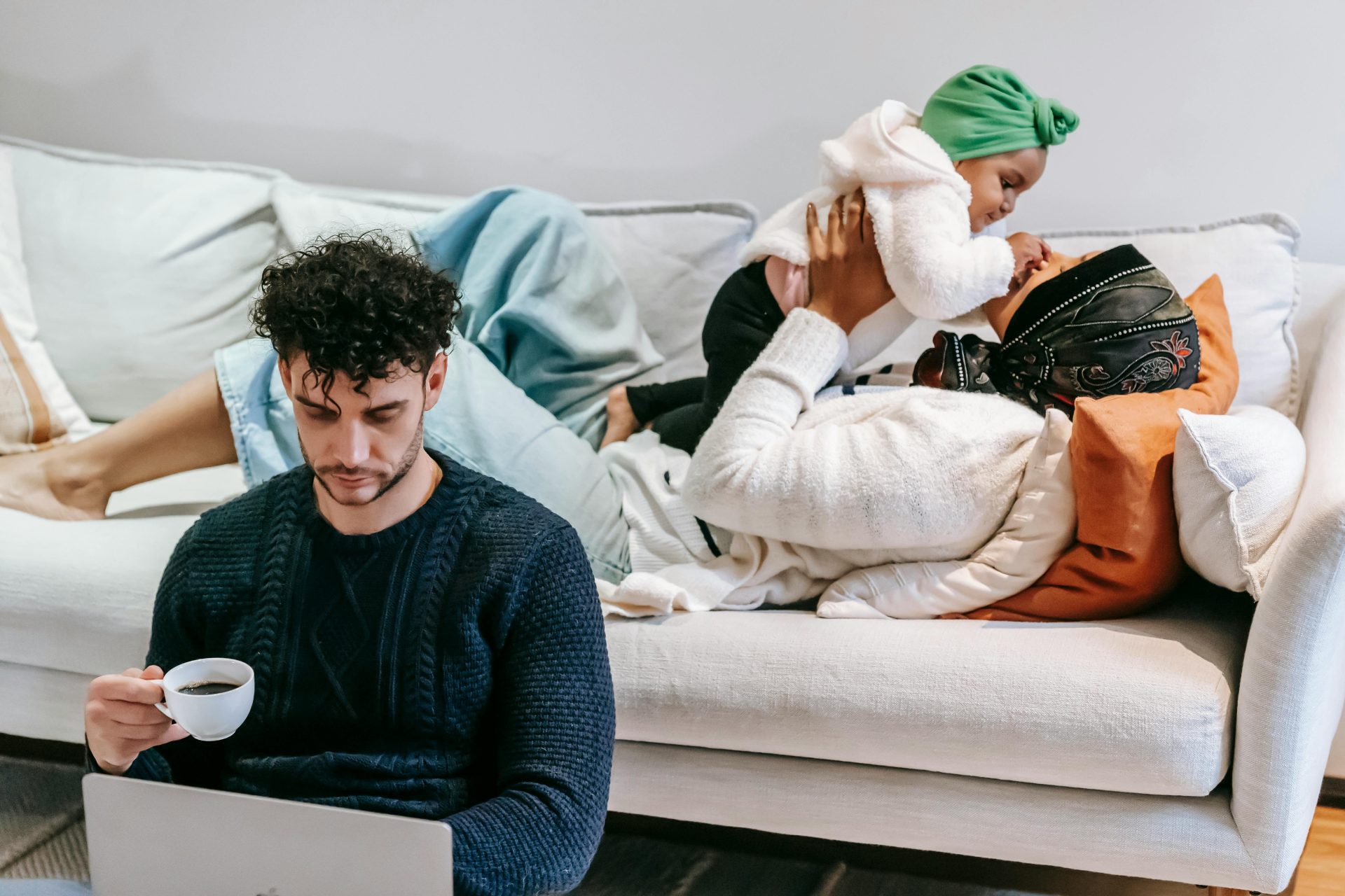 High angle of loving African American mom caressing girl while dad drinking coffee and watching netbook at home
